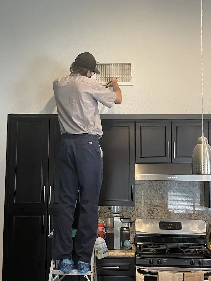 Technician inspecting an air vent during HVAC service in The Colony
